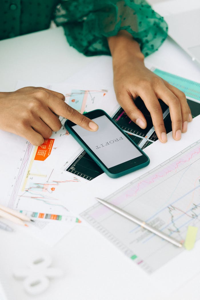 Hands analyzing financial charts using a smartphone, highlighting profit trends.